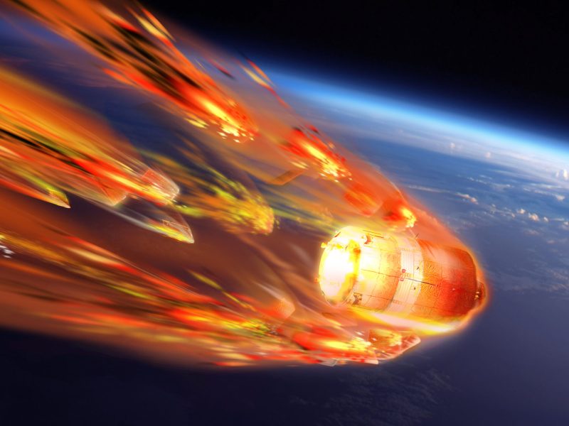 Illustration of a satellite engulfed in flames as it breaks apart while reentering the atmosphere.