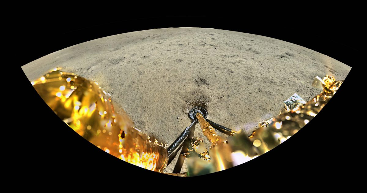 A view from the Chang'e-6 lander, showing the golden body of the spacecraft in the foreground, the impression of a landing leg in the lunar regolith, a relatively smooth lunar surface, and distant peaks and rim of Apollo crater against a black backdrop.