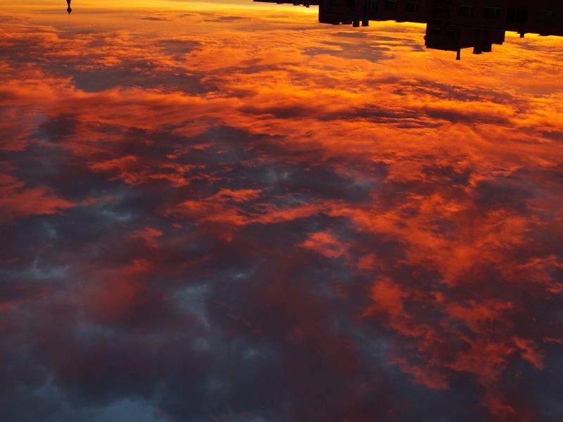 A photo taken from a space station showing Earth's cloud cover illuminated by a sunrise.