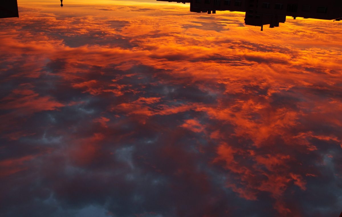 A photo taken from a space station showing Earth's cloud cover illuminated by a sunrise.